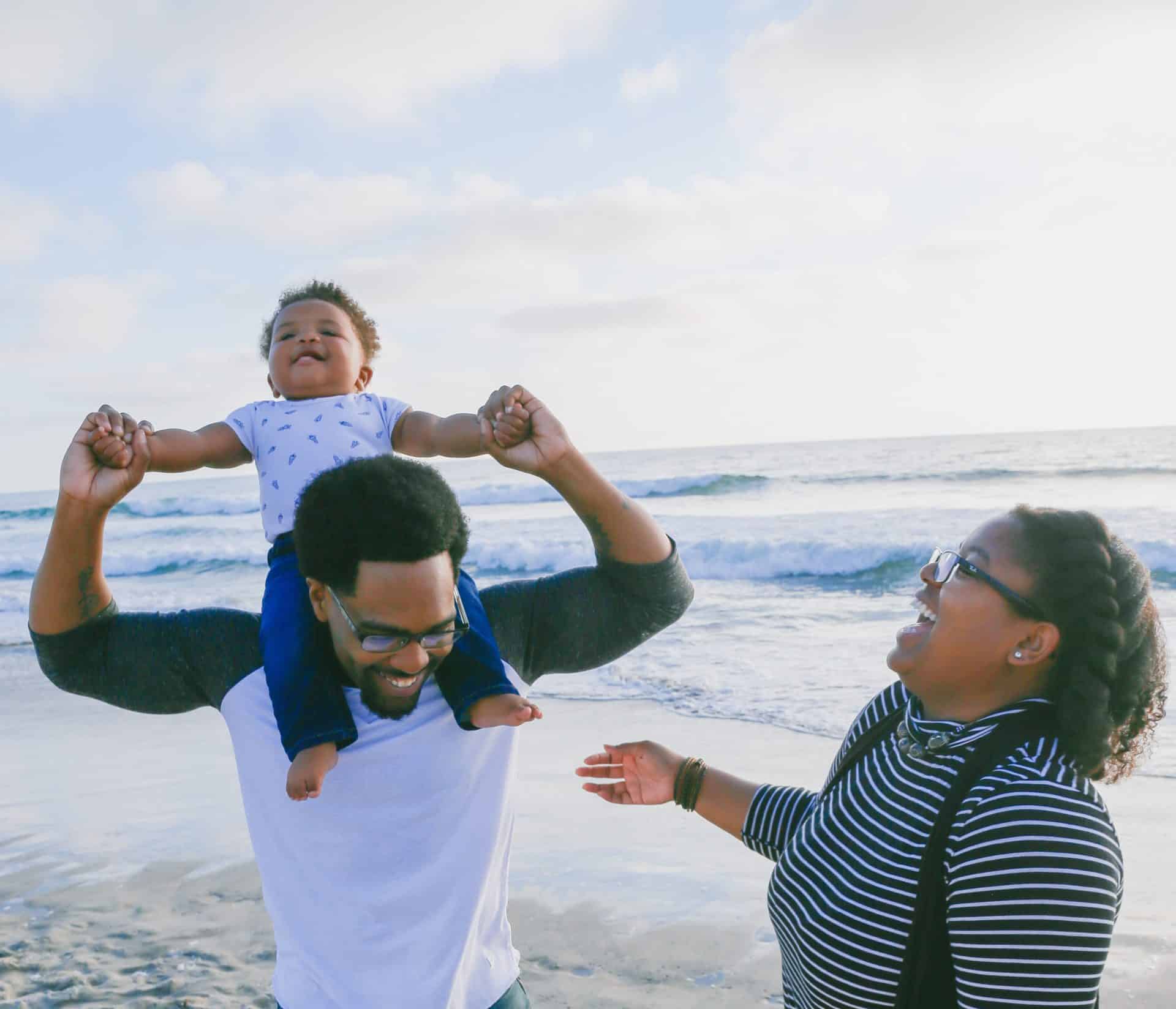 A father, mother, and child enjoy a fun beach day; the family is the answer to our societal ills.