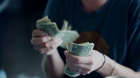 A young woman counts money.
