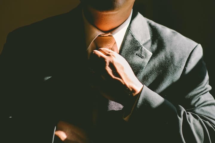 Businessman finishes tightening his tie as he prepares for work Economics according to Catholic social teaching begins with a personal gift of self and working for the common good.